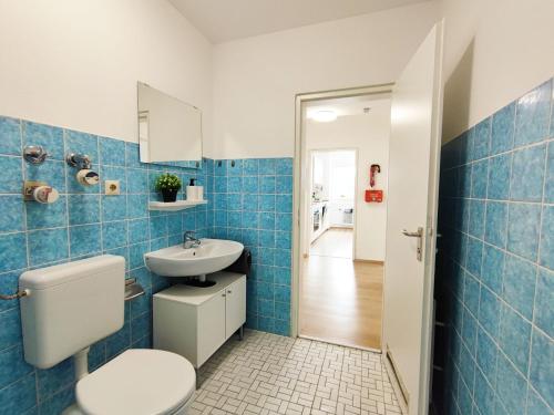 La salle de bains est pourvue de carrelage bleu, de toilettes et d'un lavabo. dans l'établissement Chic Apartment with balcony, à Bad König