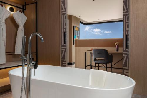 a bathroom with a white tub and a chair at Parallel Hotel Udaipur - A Stylish Urban Oasis in Udaipur