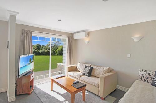 a living room with a couch and a tv at Kerikeri Park Lodge in Kerikeri