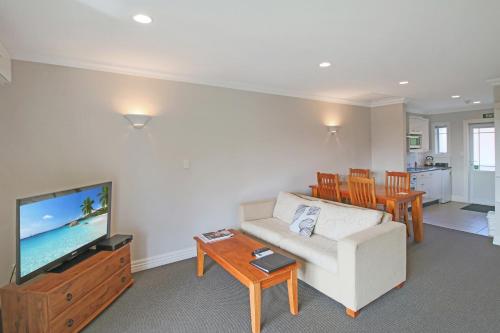a living room with a couch and a tv and a table at Kerikeri Park Lodge in Kerikeri