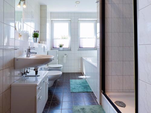 a bathroom with two sinks and a tub and a toilet at Großzügige Ferienwohnung im Haus ''Anno 2000'' in Bergen auf Rügen