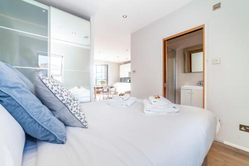 1 dormitorio con cama blanca y almohadas azules en Whitechapel, Fantastic 1Bed Apt with Stunning Views over City en Londres