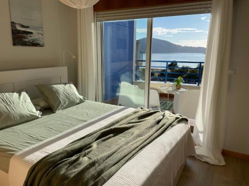 a bedroom with a bed and a large window at Apartamento con vistas al mar Urb Puerto Azul B3 in Cedeira