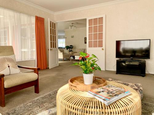 a living room with a couch and a tv and a table at Cosy House in Chartwell, Hamilton-Private Garden & Shopping Mall in Hamilton