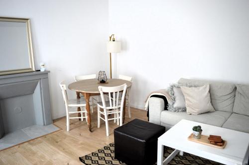 ein Wohnzimmer mit einem Sofa und einem Tisch in der Unterkunft Le Gambetta, 100m de la plage in Luc-sur-Mer