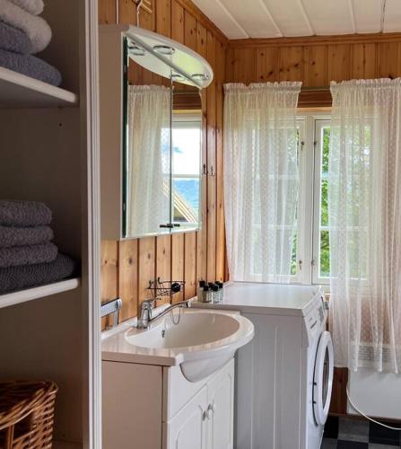 a bathroom with a sink and a mirror and a window at "SoFly Cottage", Authentic Norwegian Experience in Noresund