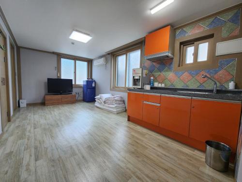 Ullŭng的住宿－e comfy Hotel，一个带橙色橱柜的厨房和一间客厅