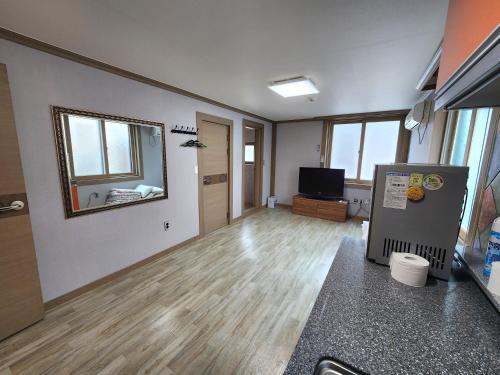 an empty living room with a television and wooden floors at e comfy Hotel in Ullŭng