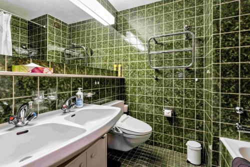 ein grün gefliestes Bad mit einem Waschbecken und einem WC in der Unterkunft Derby 26A in Arosa