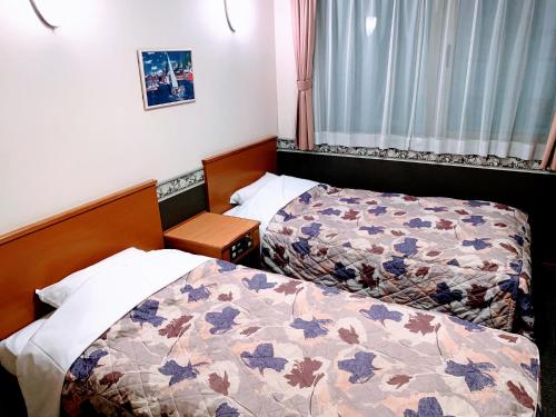 pokój hotelowy z 2 łóżkami i oknem w obiekcie Business Hotel Ekimae w mieście Hakodate