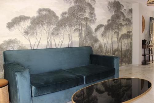eine blaue Couch in einem Wohnzimmer mit einem Wandbild von Bäumen in der Unterkunft San Clemente House in Sevilla