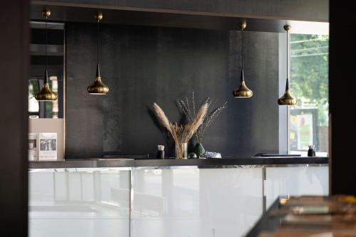 a kitchen with white cabinets and gold pendant lights at Best Western Plus Plaza Hotel Graz in Graz