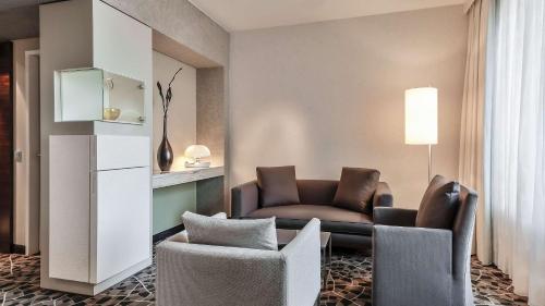 a living room with a couch and two chairs at Dorint Hotel am Heumarkt Köln in Cologne