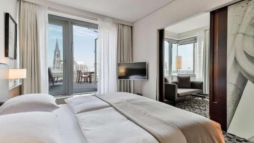 a bedroom with a large bed and a large window at Dorint Hotel am Heumarkt Köln in Cologne