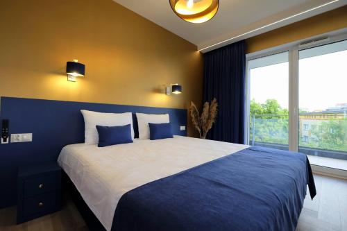 - une chambre avec un grand lit aux murs bleus et une fenêtre dans l'établissement Apartamenty Centrum Premium Gold, à Białystok