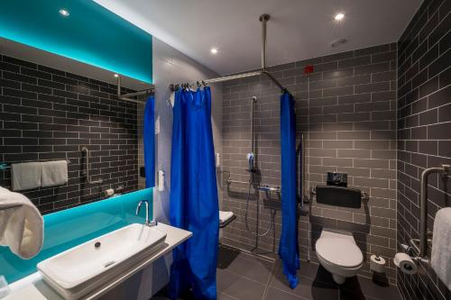 ein Badezimmer mit einem blauen Duschvorhang und einem WC in der Unterkunft Holiday Inn Express - Luzern - Kriens, an IHG Hotel in Luzern