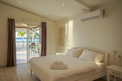a bedroom with a large white bed and a balcony at Serenity by the Sea- 3BRVilla w Stunning Sunsets in Tamarin