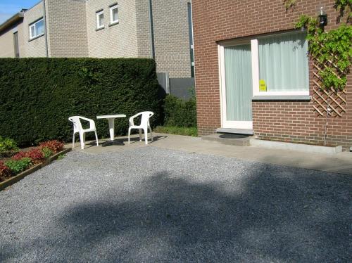 two white chairs sitting in front of a building at Liry's Home in Tongeren