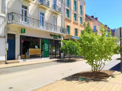 a street with a building and a tree in front at Le T3 Confort - Au Cœur de Montceau in Montceau-les-Mines