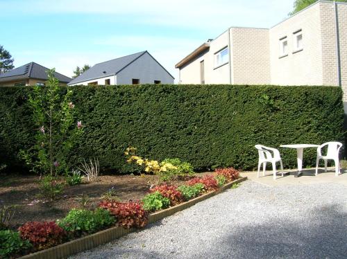 a garden with a table and chairs in front of a hedge at Liry's Home in Tongeren