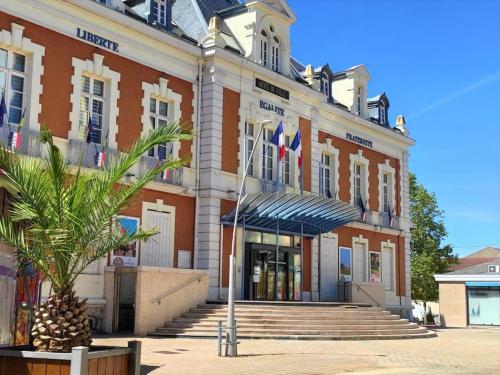 a building with a palm tree in front of it at Le T3 Confort - Au Cœur de Montceau in Montceau-les-Mines