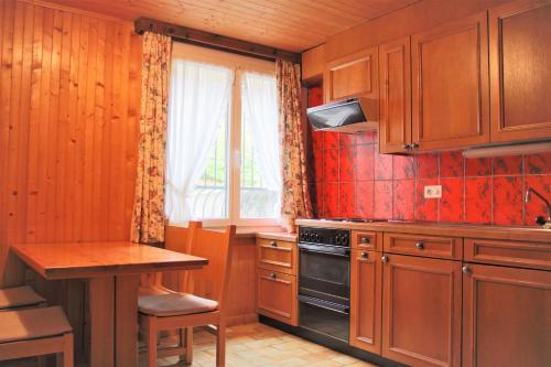 cocina con armarios de madera, mesa y ventana en Self service Guesthouse Berggeist, en Saas-Fee