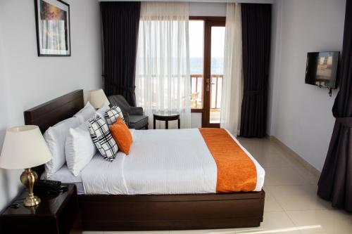 a bedroom with a bed with an orange blanket and a window at Destination Beach Hotel by Dreamworld in Karachi