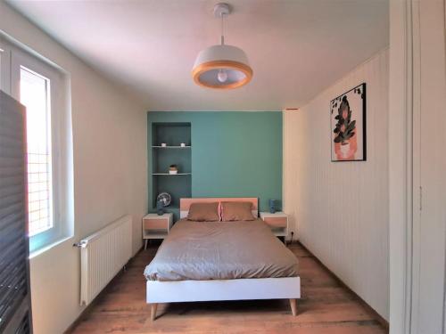 une chambre avec un lit et un mur bleu dans l'établissement Le T1 Confort - Au Coeur de Montceau, à Montceau-les-Mines