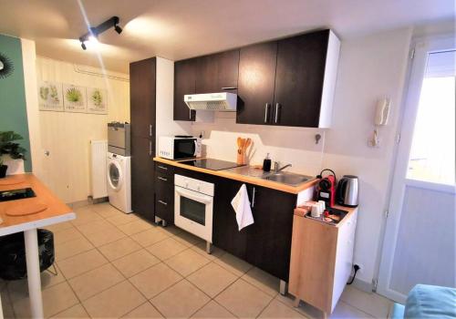 une cuisine avec un évier et une cuisinière four supérieur dans l'établissement Le T1 Confort - Au Coeur de Montceau, à Montceau-les-Mines