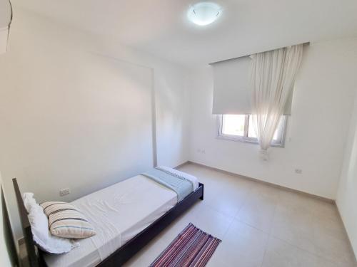 a white bedroom with a bed and a window at Seaside Elegance Retreat in Larnaka