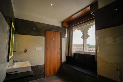 a bathroom with a sink and a wooden door at The Ekling Garh Hotel & Resort in Udaipur