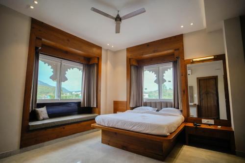 a bedroom with a bed and a mirror and windows at The Ekling Garh Hotel & Resort in Udaipur