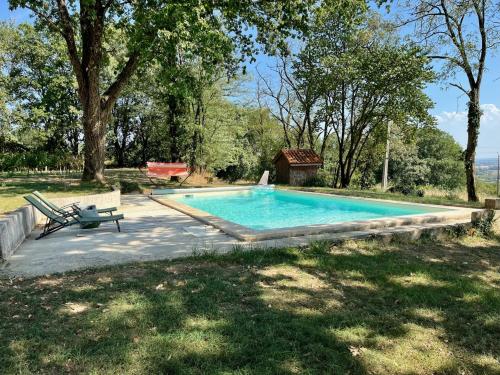 una piscina en un patio con un banco y árboles en Maison au Jude en Lamothe-Landerron