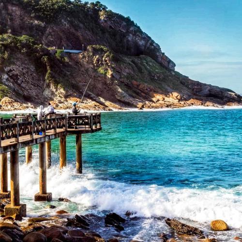 people fishing on a pier over the ocean at Luxury Beachhouse Villa II in Wilderness