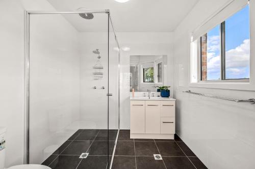 a white bathroom with a shower and a sink at Townhouse on The Hill in Newcastle