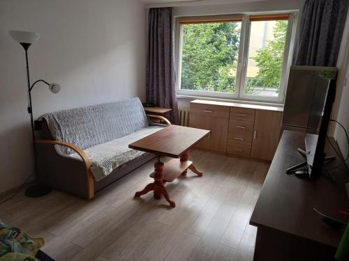 ein Wohnzimmer mit einem Sofa, einem Tisch und einem Fenster in der Unterkunft Sunset Studio in Danzig