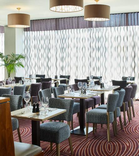 ブラッドフォードにあるLeonardo Hotel Bradfordのダイニングルーム(テーブル、椅子、カーテン付)