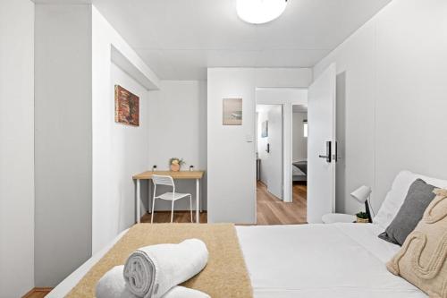 a white bedroom with a bed and a table at Private Grannyflat Room In Maroubra in Sydney