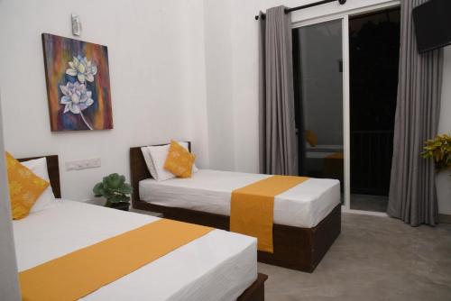 a room with two beds and a sliding glass door at Everdew Kandy Rooms in Kandy