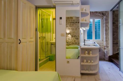 a bathroom with a bed and a sink and a shower at Apartments Kaja in Trogir