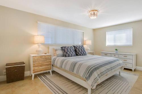1 dormitorio con 1 cama, mesita de noche y 2 ventanas en 3 Bed 2 Bath - North Palm Beach, en North Palm Beach
