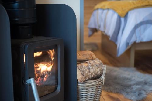 a wood stove in a room with a bed at Fern - Beacon View Pods in Knighton