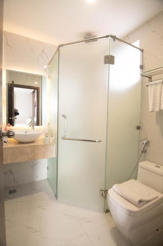 a bathroom with a shower and a toilet and a sink at Gold Central Hotel by Haviland in Da Nang