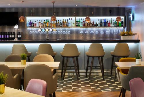 a bar in a restaurant with tables and chairs at Leonardo London Heathrow Airport in Hillingdon