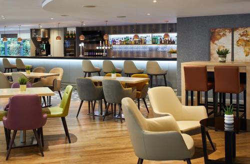 a restaurant with tables and chairs and a bar at Leonardo London Heathrow Airport in Hillingdon