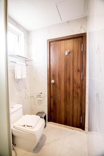 a bathroom with a toilet and a wooden door at Gold Central Hotel by Haviland in Da Nang