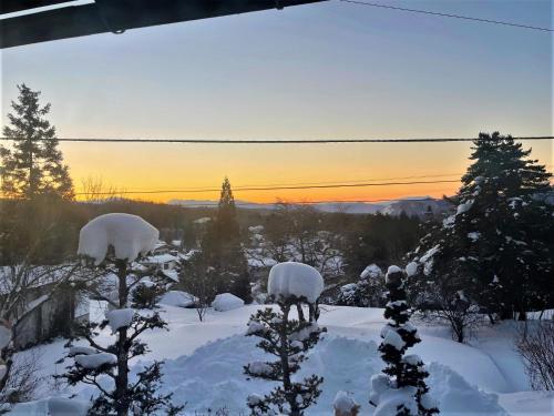 two sheep standing in the snow with the sunset in the background at 宿屋白金家 yadoya-shiroganeya 1日1組限定2名から8名様まで 全館貸切り 伝統的建造物の旅籠宿 Traditional culture experience in Nagano
