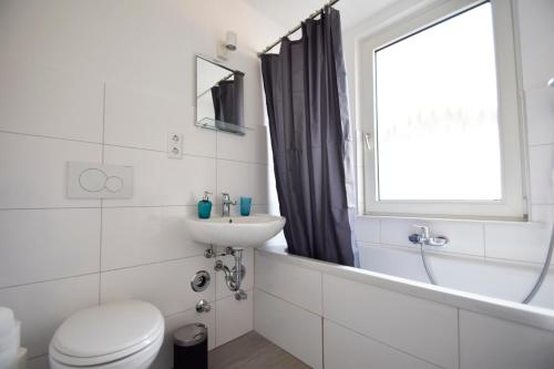 La salle de bains est pourvue d'un lavabo, de toilettes et d'une fenêtre. dans l'établissement Air Apartments 4, à Brême