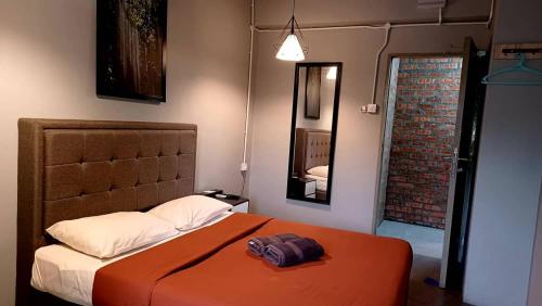 1 dormitorio con 1 cama con manta naranja y espejo en BRICKS Cameron Hostel, en Tanah Rata