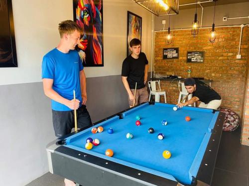 een groep mannen die rond een pooltafel staan bij BRICKS Cameron Hostel in Tanah Rata